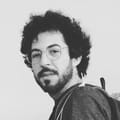 Saulo Vallory: curly dark hair, round glasses and a beard, in a black-and-white photo.